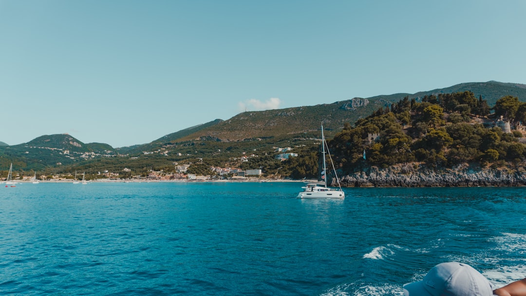 Sailboat on blue water near green coastline